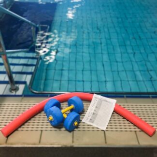 This image shows part of the Hydrotherapy pool, with some equipment, a pool noodle, aquatic hand weights, and an exercise program.